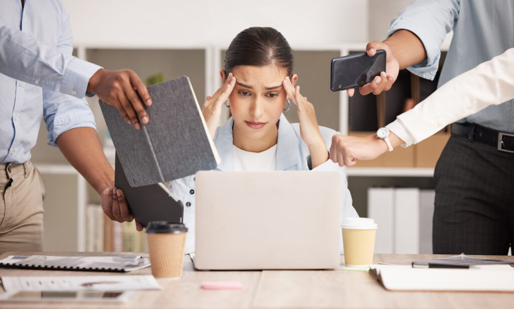 Junge Frau am Arbeitsplatz mit viel Arbeit und Stress